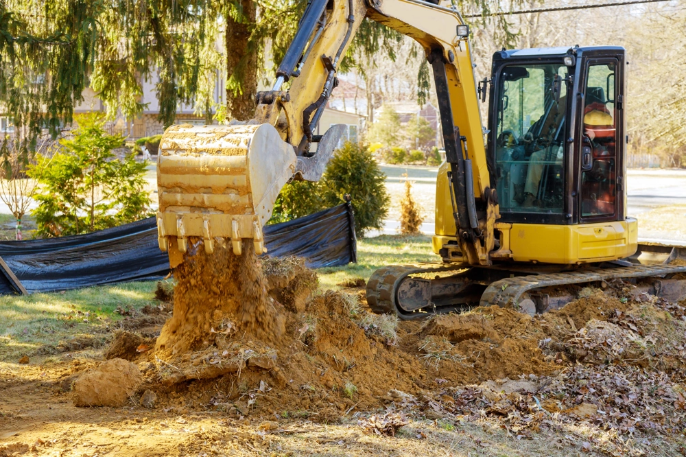 Minikoparka wyrównuje teren w ogrodzie – usługi minikoparką